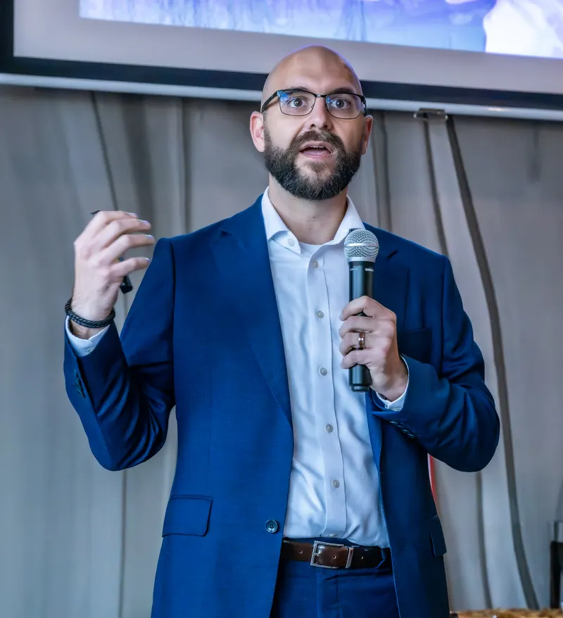 Nic Zateslo speaking on stage with a microphone